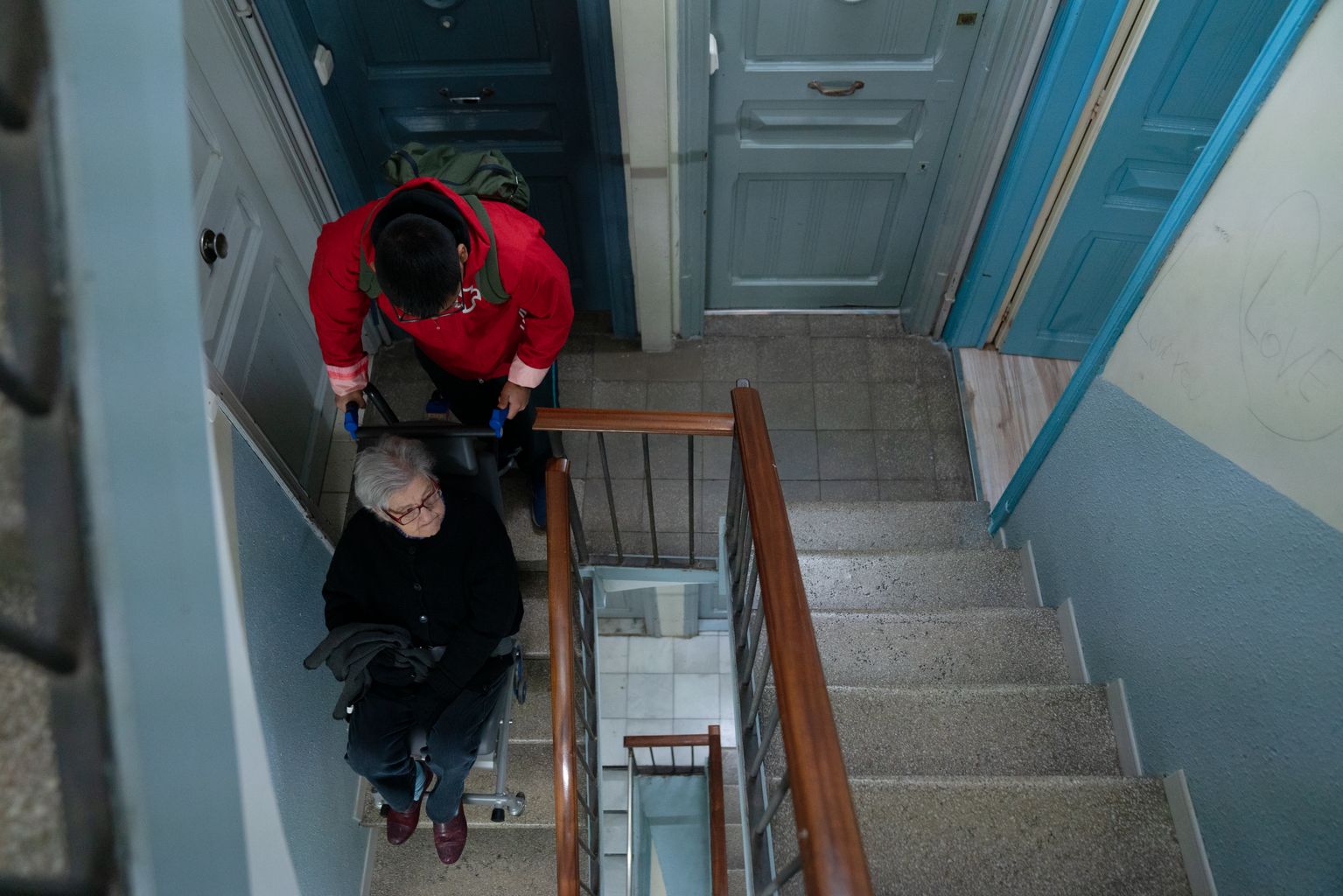 Un miembro de la Cruz Roja, ayudado por una máquina, sube a Carmen a su domicilio