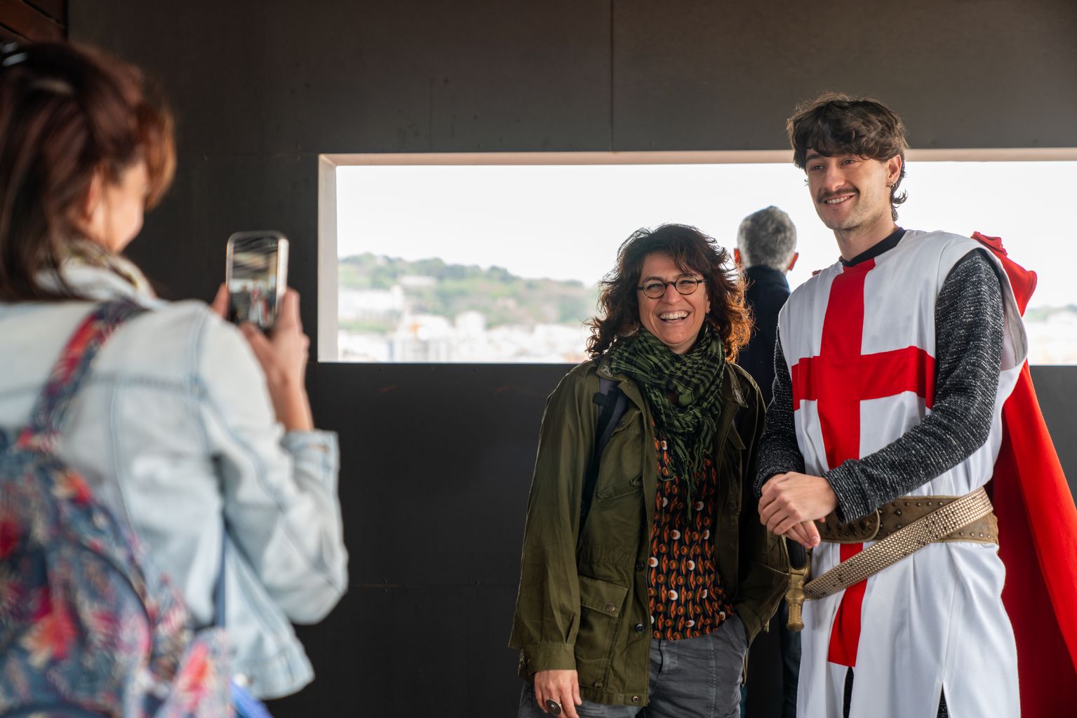 Un actor vestit de sant Jordi es fotografia amb els assistents durant la jornada de portes obertes de l’Ajuntament de Barcelona amb motiu de la diada de Sant Jordi. Fan fotografies des del mirador de Maria Aurèlia Capmany.