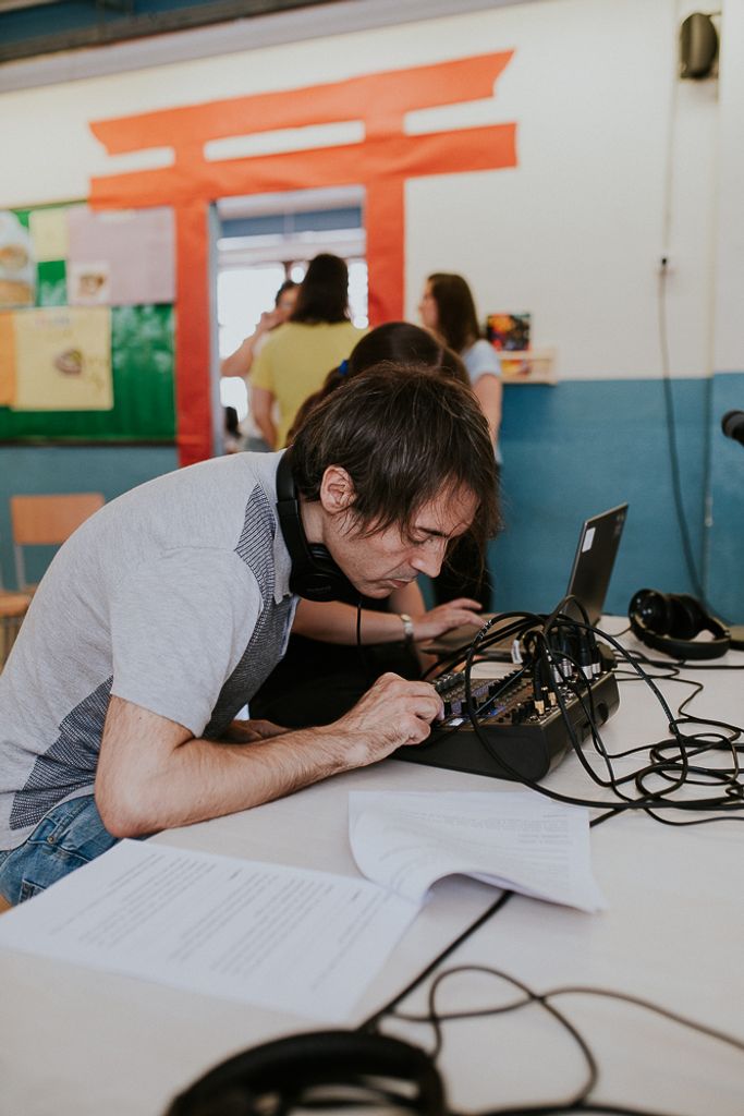 Un tècnic de so ajusta paràmetres d’una taula de so en una aula escolar.