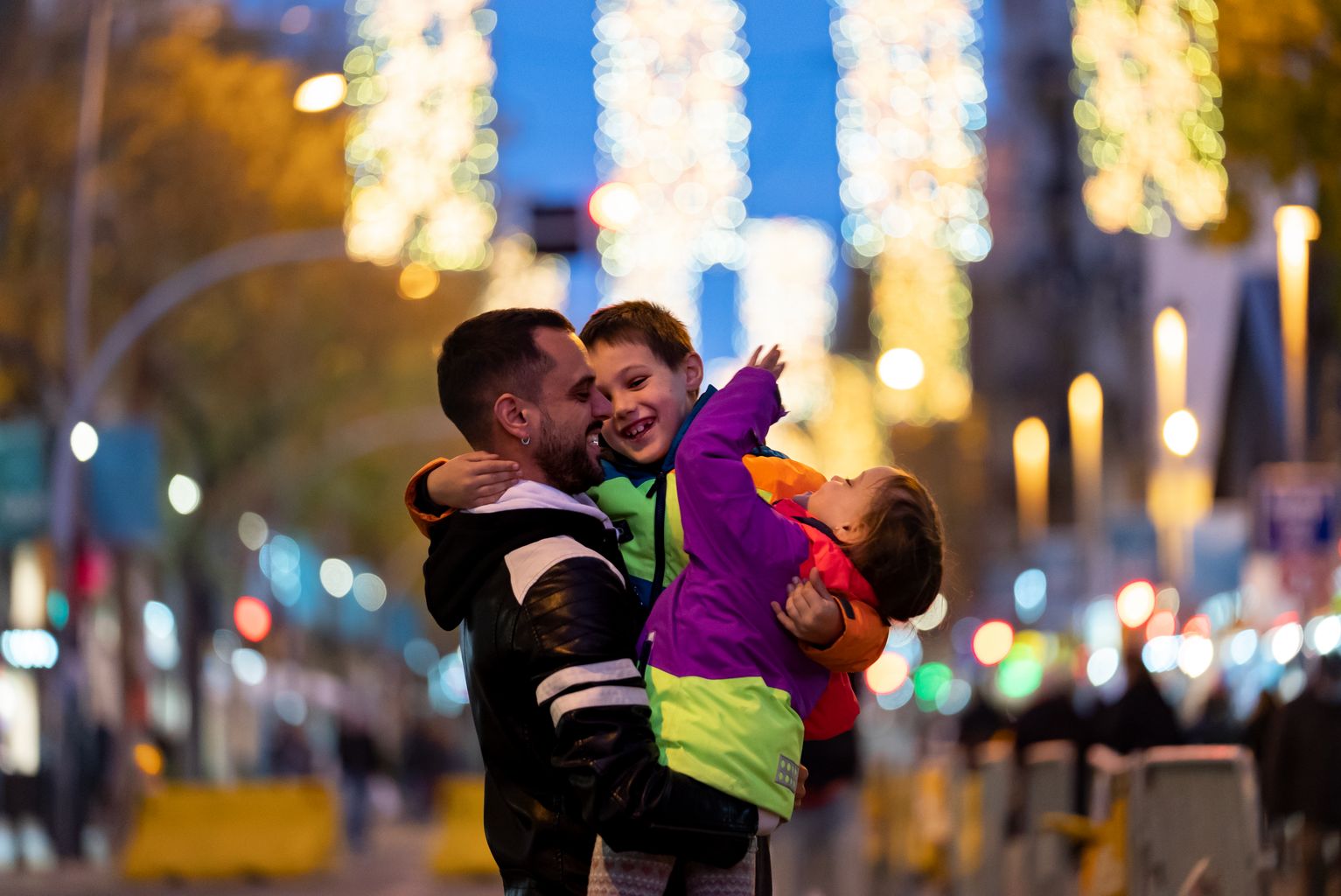 Familia en la calle Creu Coberta bajo las luces de Navidad