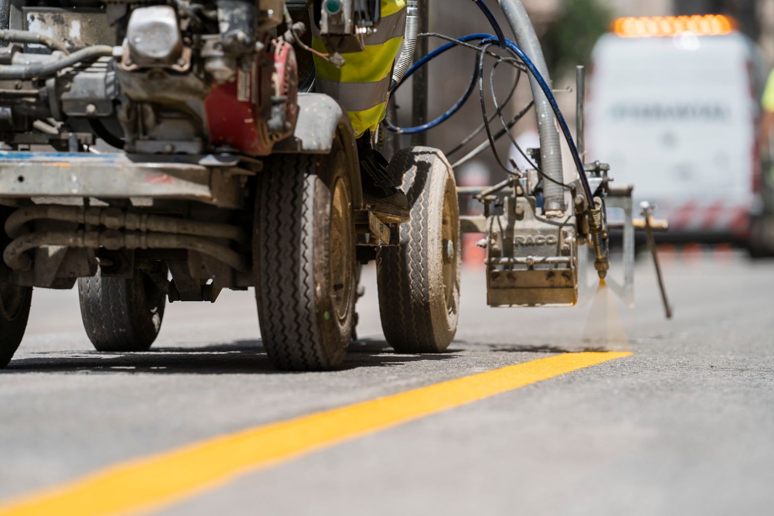 Detall de la màquina que pinta la línia groga contínua sobre l'asfalt de l'obra d'ampliació de voreres de la via Laietana