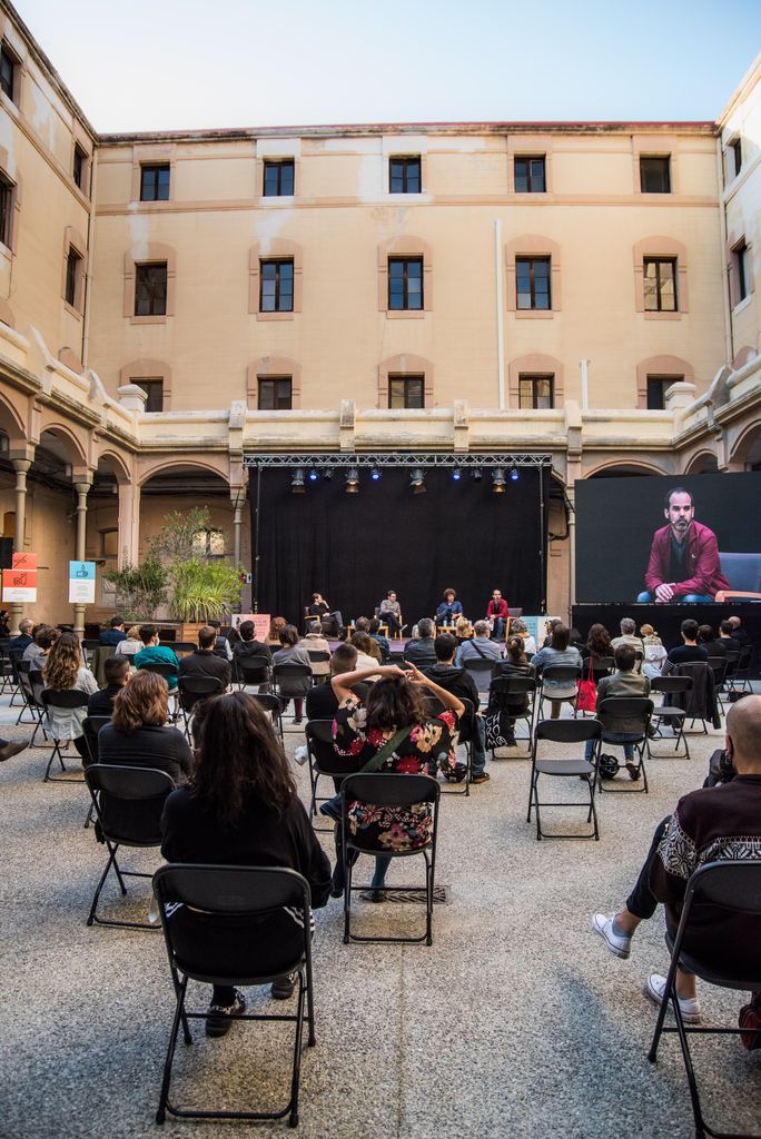 Taula rodona "La temptació autoritària. El desafiament de la nova dreta radical" a la Model. Vista del públic i de l'escenari amb una gran pantalla al lateral on es pot seguir la intervenció de Rubén Martínez Moreno