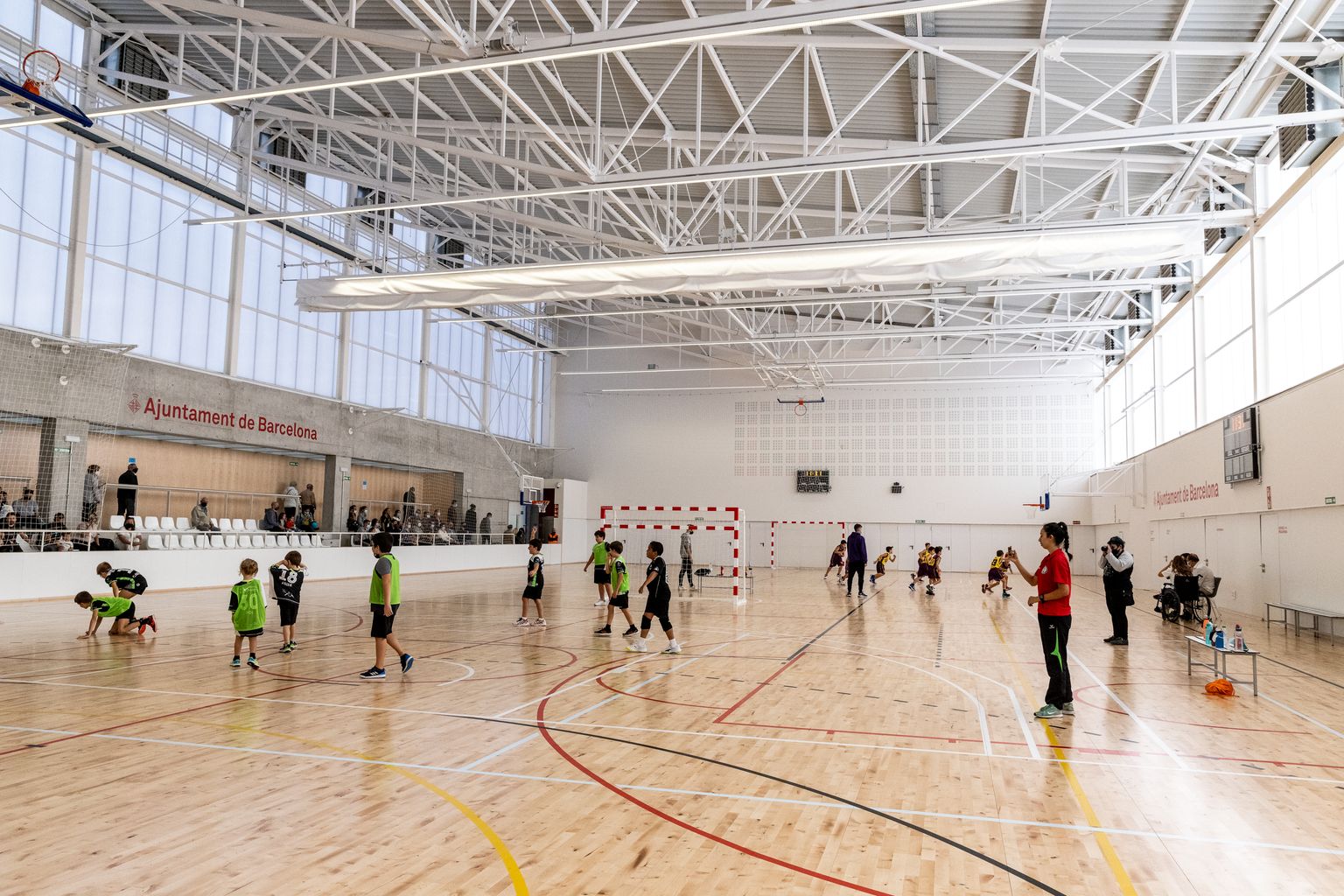 Infants jugant a handbol a la pista interior del Poliesportiu La Sagi durant la inauguració de l'equipament