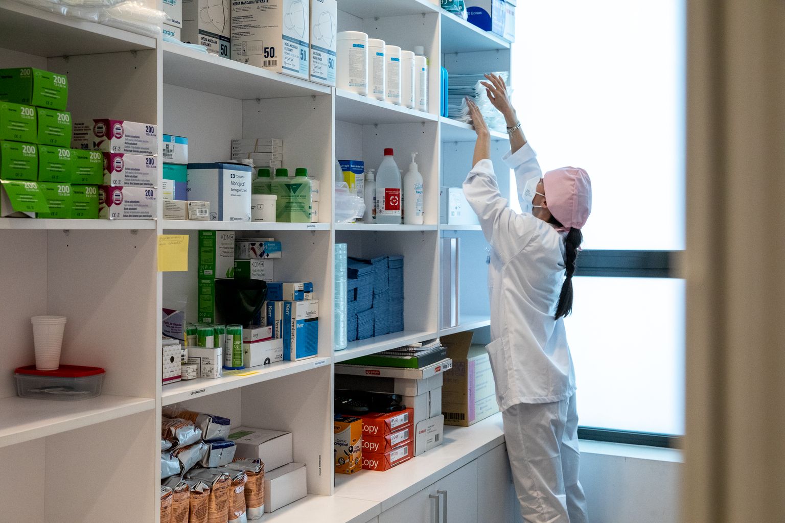 Una sanitària agafa uns paquets de material odontològic dels prestatges amb subministraments mèdics