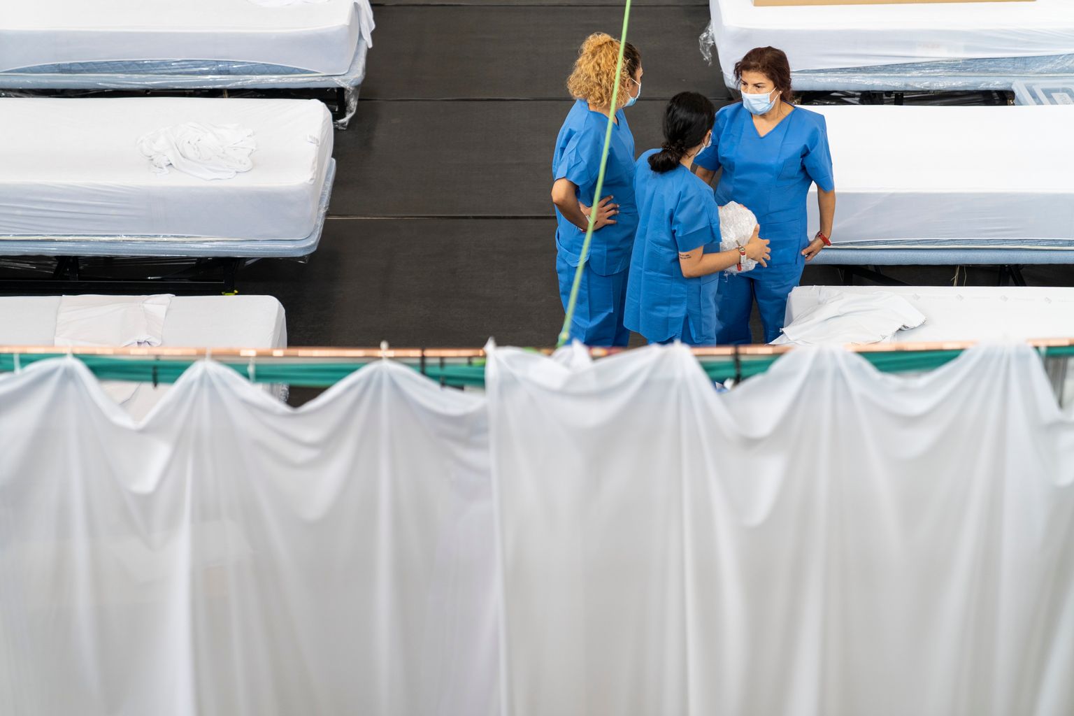 Pavelló Salut Guinardó. Personal sanitari conversa en una de les sales per coordinar-se enmig de la tasca de fer els llits