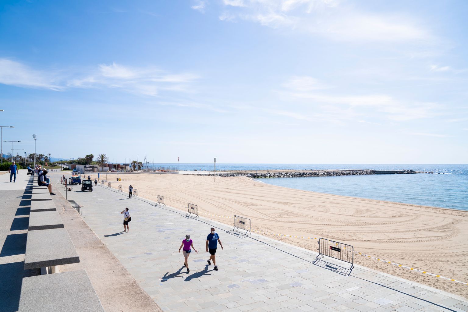 Persones caminen i fan exercici pel passeig Marítim del Bogatell mentre la platja roman tancada