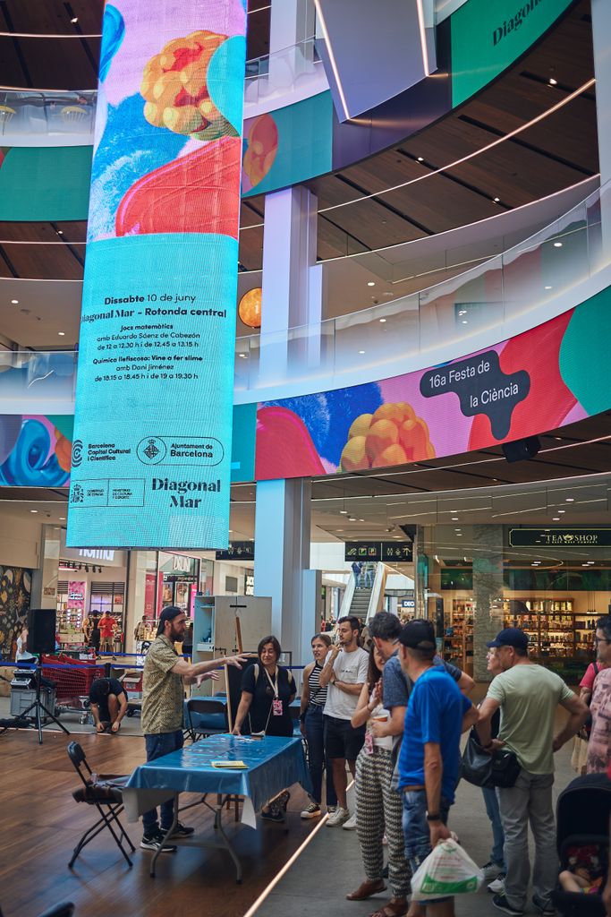 Gente participando en la demostración "Juegos matemáticos para ganar siempre" de la 16.ª Fiesta de la Ciencia en el centro comercial Diagonal Mar.