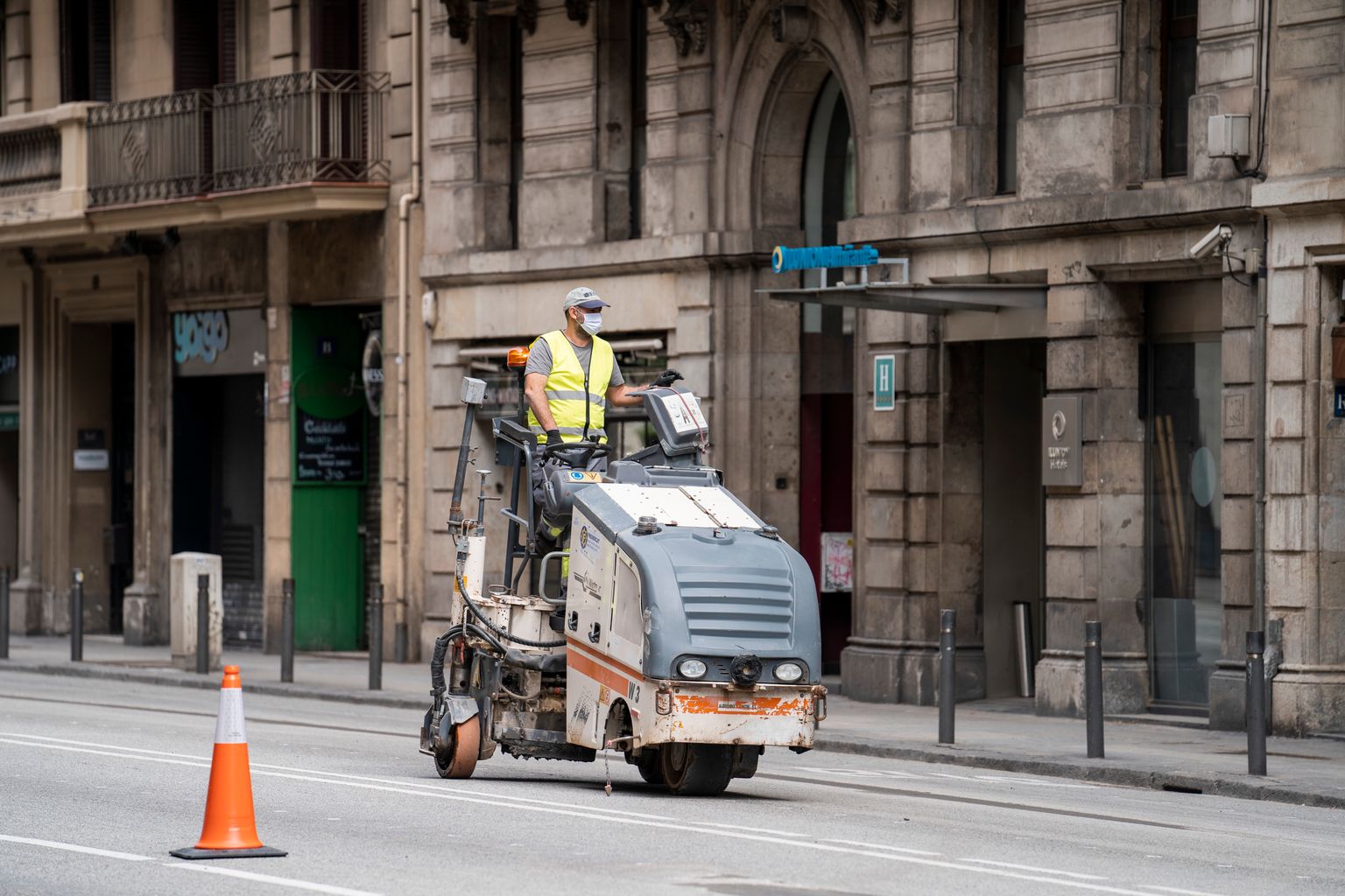 Un operari amb una màquina fresadora treballa sobre l'asfalt de la via Laietana durant les obres d'ampliació de les voreres