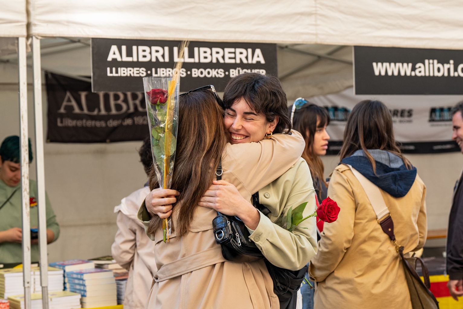 Dos chicas se abrazan con rosas en las manos el Día de Sant Jordi
