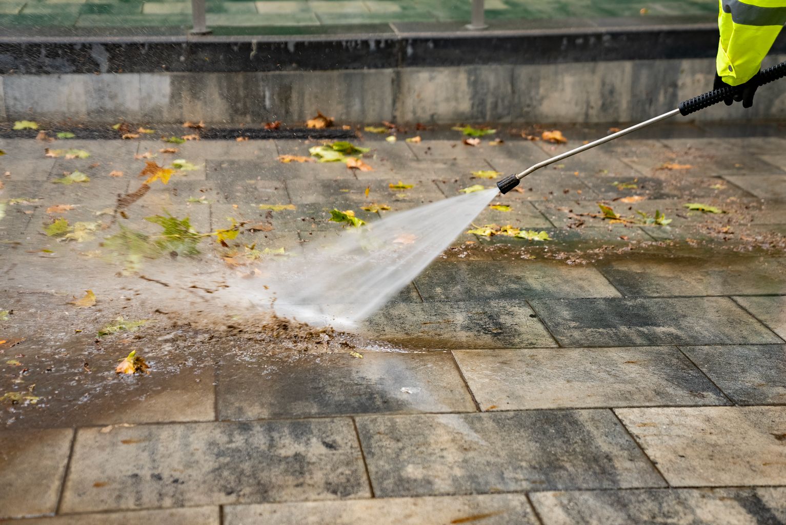 Un trabajador del Servicio de Limpieza lava con agua a presión el pavimento de la plaza de la Trinitat y retira hojas, tierra y suciedad