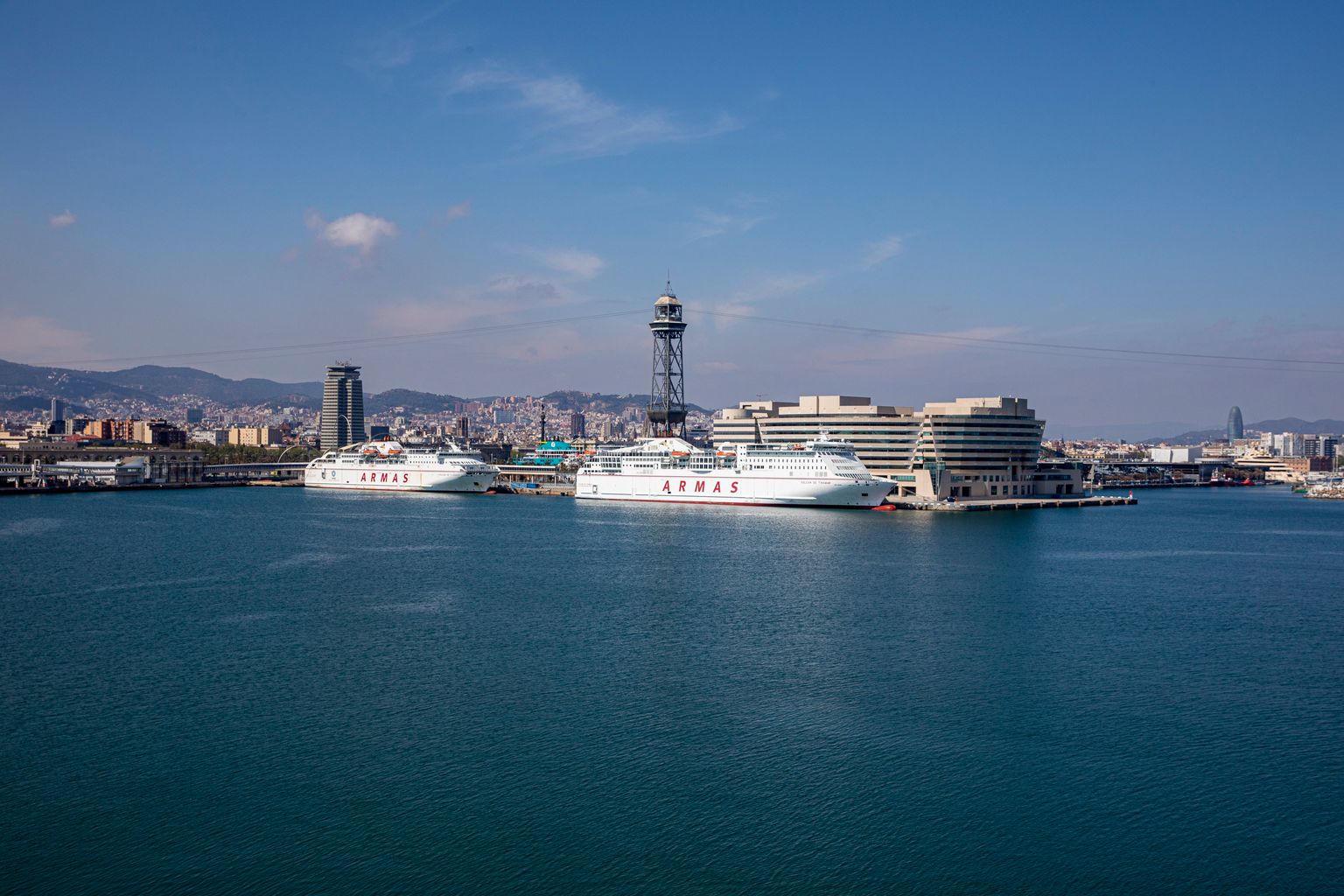 Port de Barcelona sense activitat amb dos vaixells amarrats i la torre de Jaume I al fons. Barri de la Barceloneta.