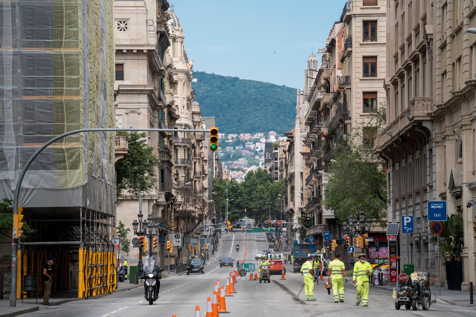 Treballadors durant les obres d'ampliació de les voreres de la via Laietana als carrils de circulació sentit muntanya tallats. Pel carril de baixada passen els vehicles