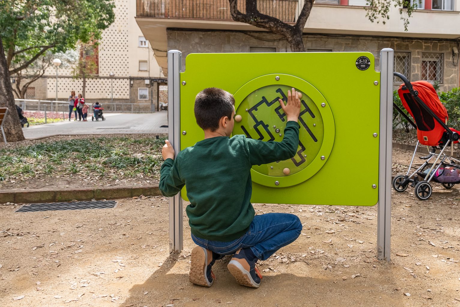 Una niña juega con un laberinto de madera en la nueva área de juego infantil accesible de los jardines de Massana
