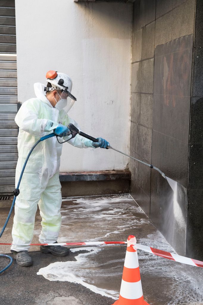 Un treballador del Servei de Neteja renta amb aigua a pressió les parets del Mercat de les Corts