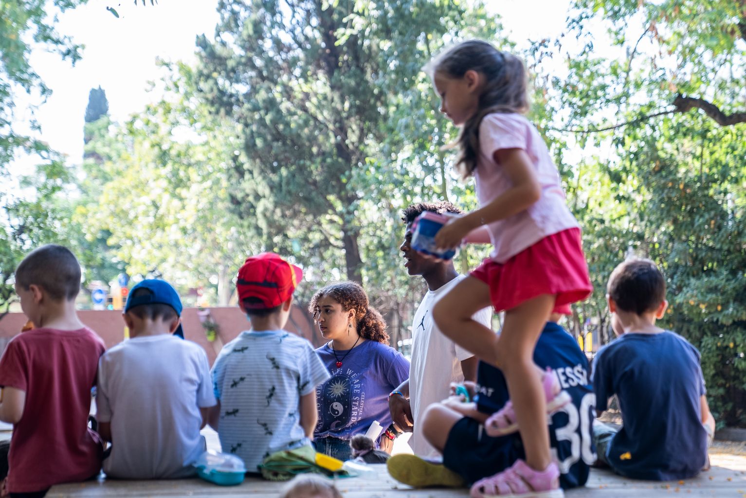Una monitora y un monitor coordinando su grupo de niños y niñas durante el inicio de la campaña de actividades de verano para niños y niñas en la Escuela Turó Blau.