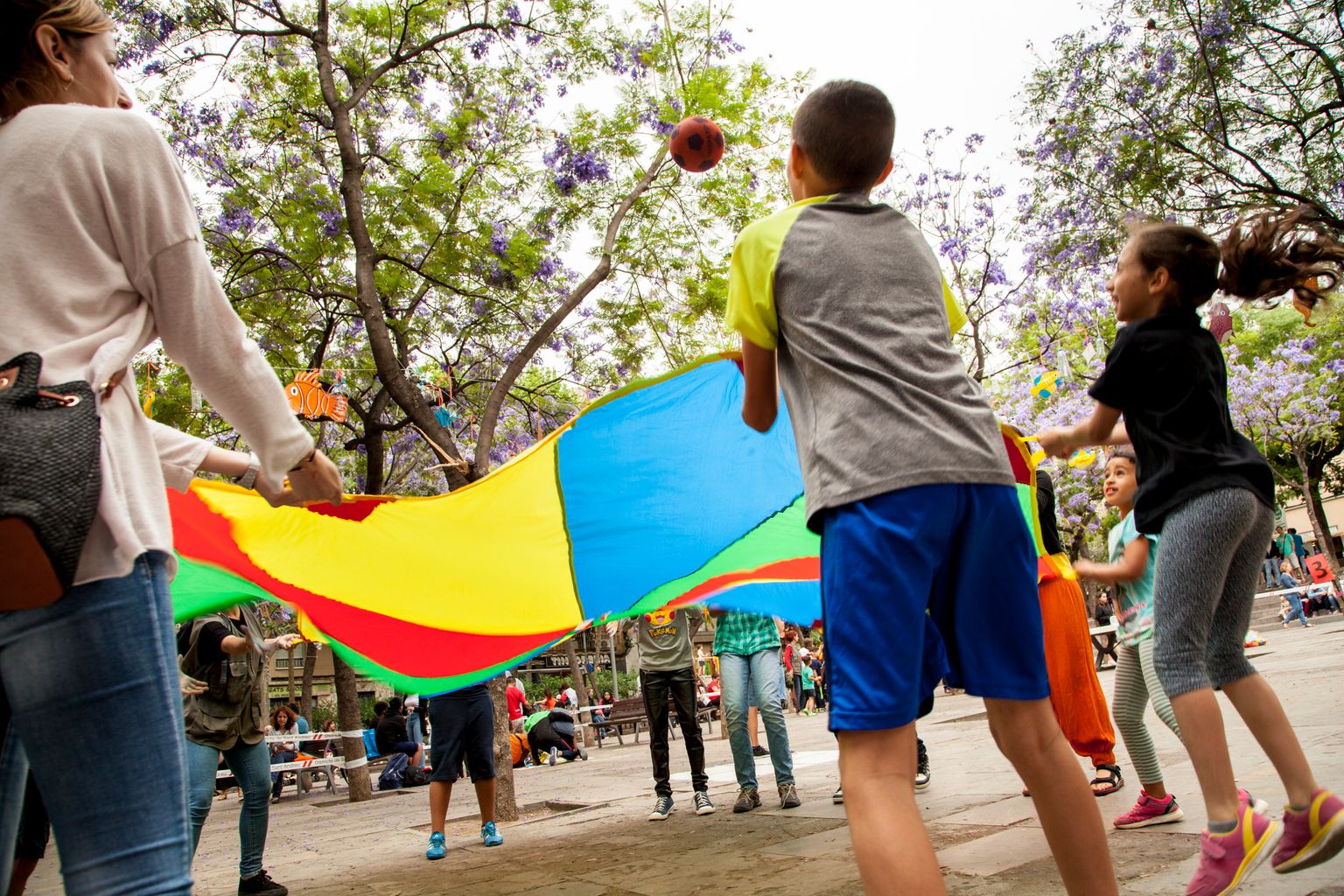 Uns nens jugant amb una tela de colors que fa volar una pilota durant la presentació del Pla de Barris de la Trinitat Vella