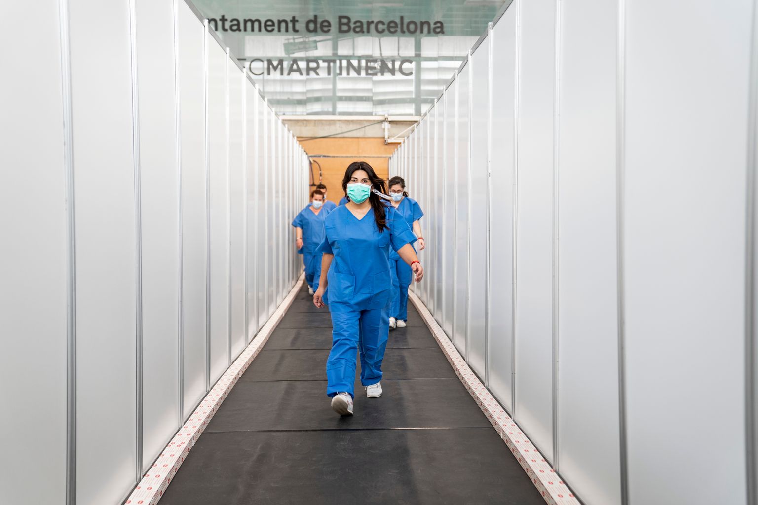 Personal sanitario caminando, entre los paneles, por uno de los pasillos que ya está cubierto con un suelo de goma