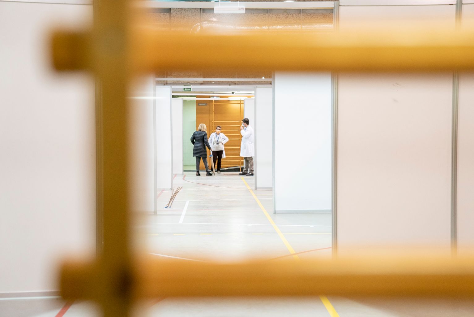 Pavelló Salut Claror. Emplafonat sobre la pista i, al fons, responsables sanitaris conversant