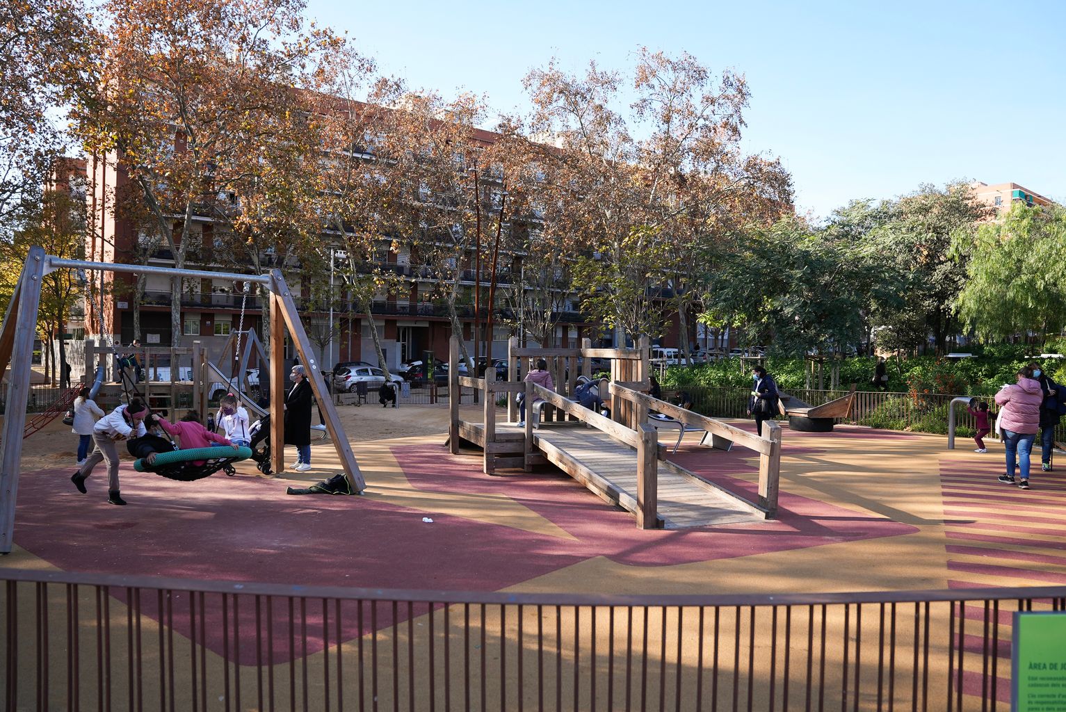 Infants jugant a l'àrea de joc infantil del parc de la plaça de Sóller als gronxadors. Hi ha una petita barca