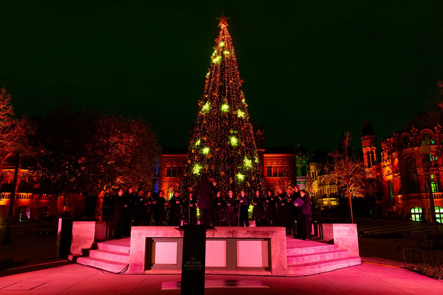 Actuació dun cor de cant durant l’acte d’inauguració de l'enllumenat nadalenc de l'Hospital de Sant Pau. Al darrere, un arbre de Nadal il·luminat