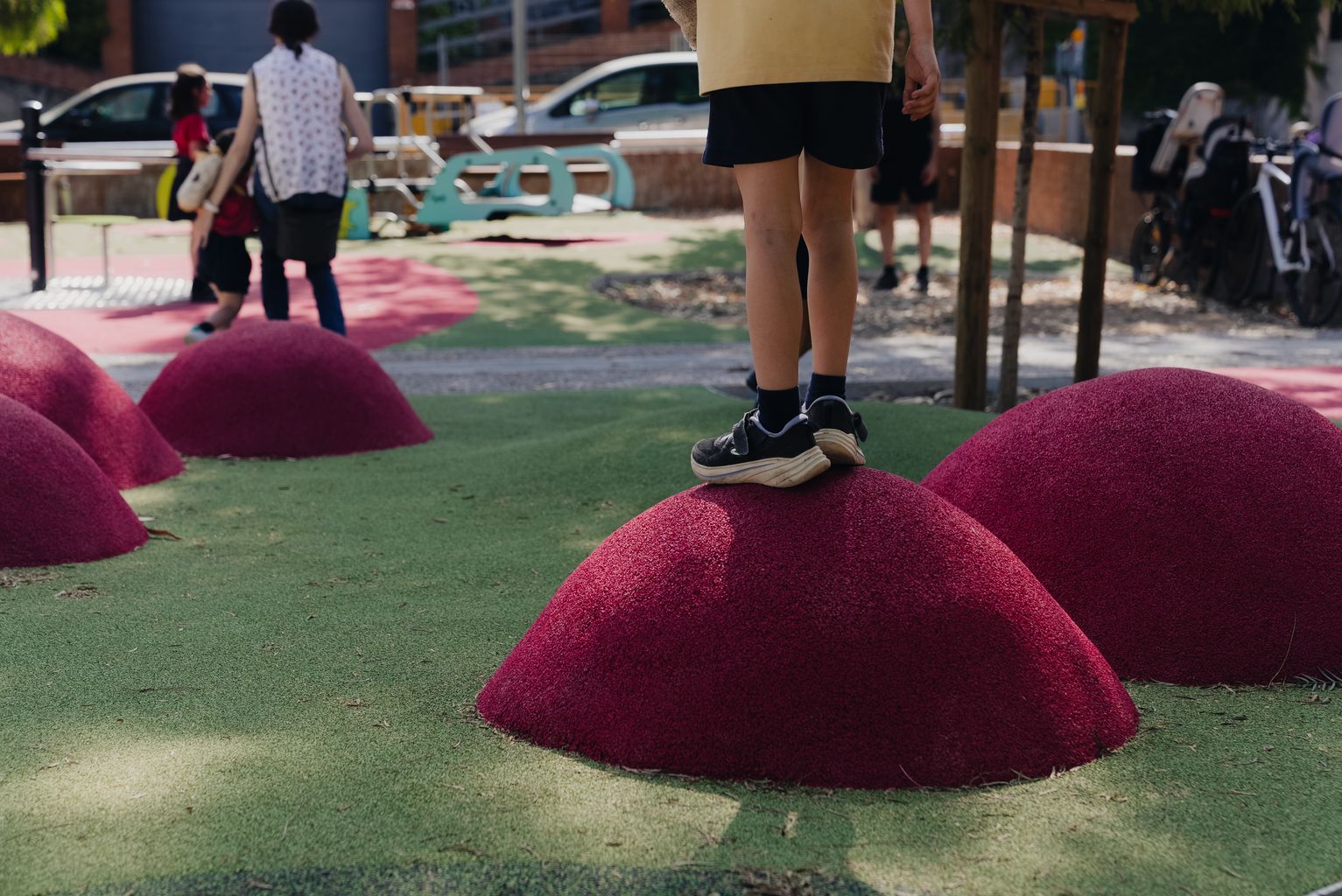 Niños subidos a unas minicolinas de goma, que están en el espacio de juego de la plaza de Emili Mira