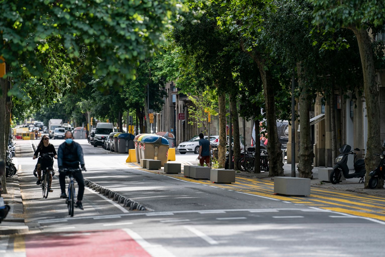 Vista del carrer del Consell de Cent amb ciclistes pel carril bici i bancs sobre la nova zona ampliada per a vianants pintada