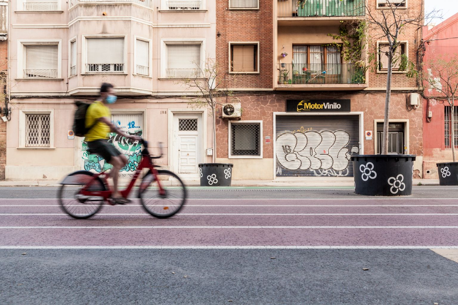 Carrer dels Almogàvers amb una part pintada com si fos una pista d’atletisme, per on circula un ciclista