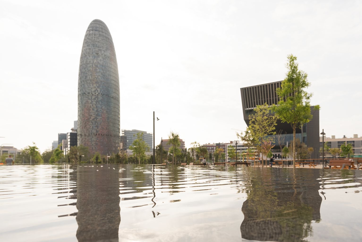 Mirall d'aigua del nou parc de les Glòries i de fons el Museu del Disseny de Barcelona (DHub Barcelona) i la Torre Glòries