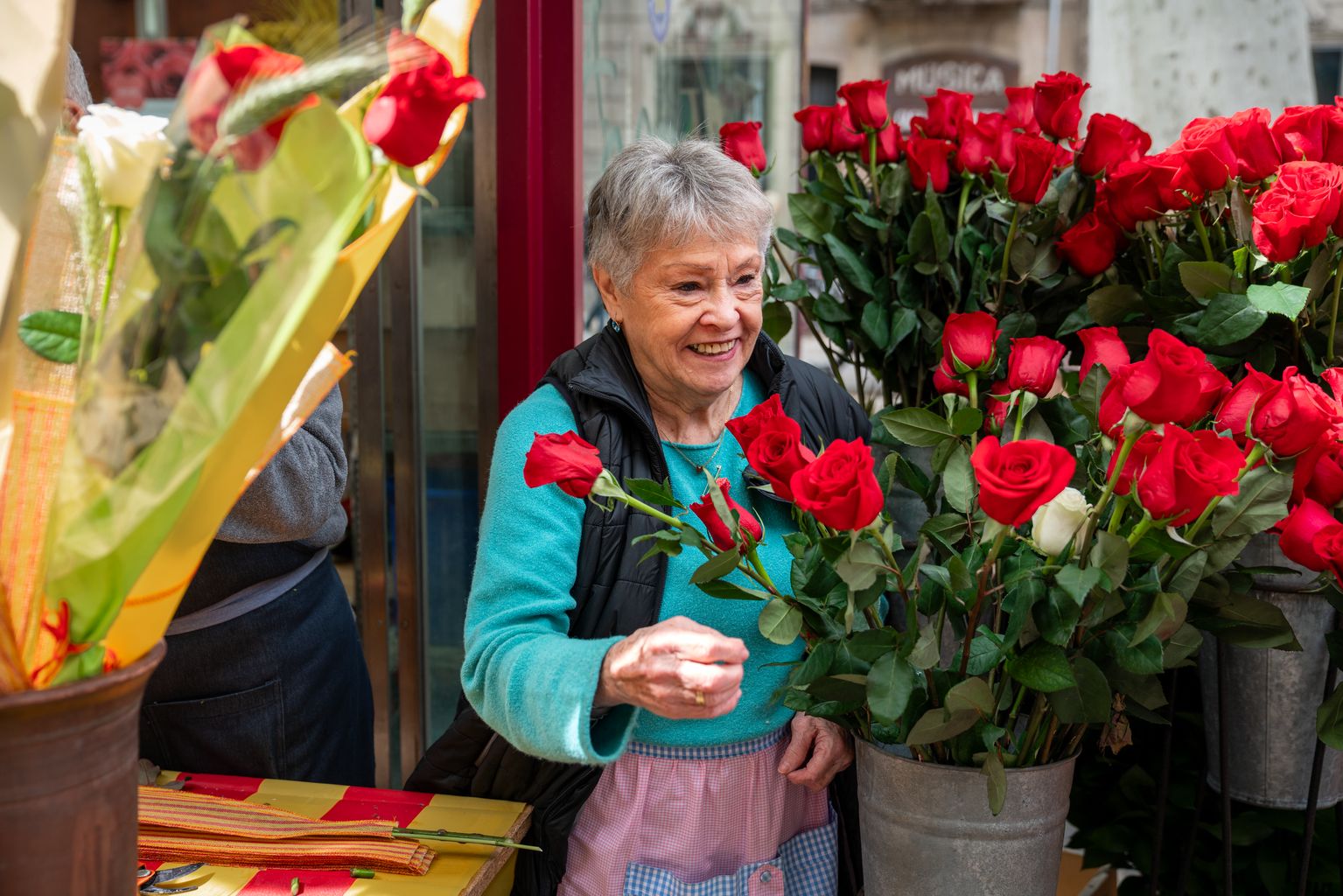 Una mujer mayor prepara rosas en un puesto de La Rambla.