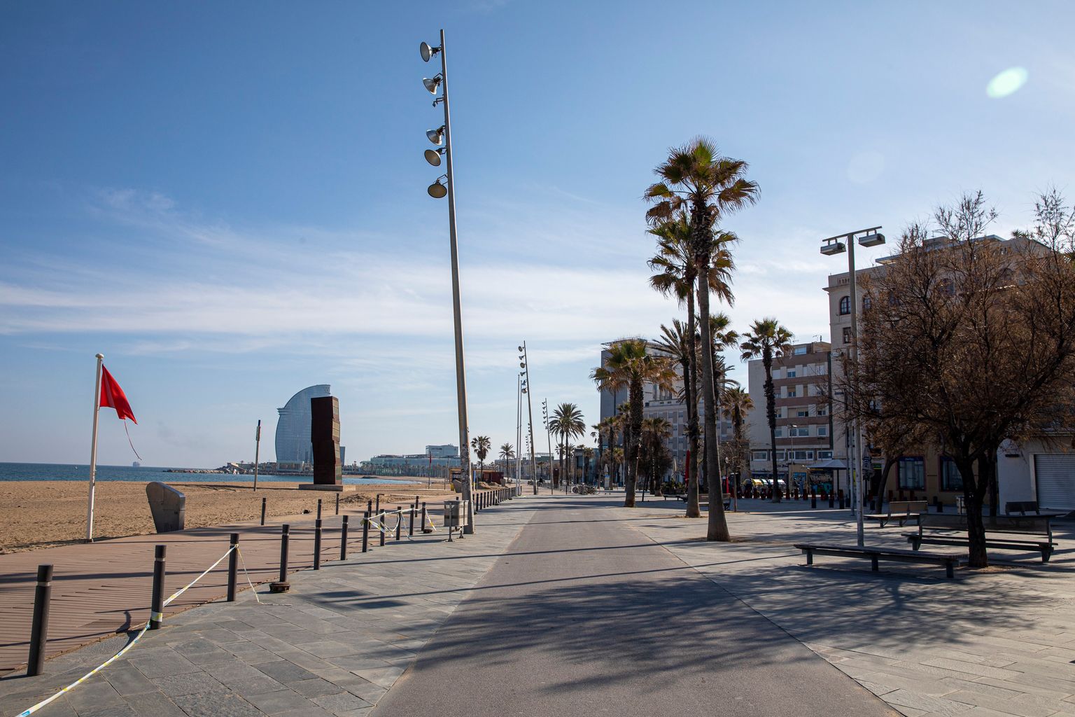 Passeig Marítim de la Barceloneta sense gent, amb la bandera vermella onejant a les platges. Barri de la Barceloneta.