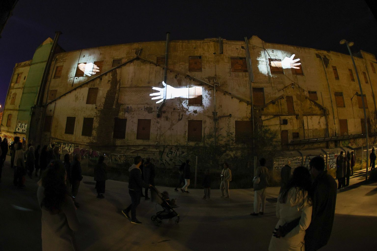 Tres mans projectades a la façana d'un edifici. “Behind the walls”, obra de Nathalie Maufroy. A la Casa de les Lletres - pl. Dolors Piera (Sancho de Ávila, 135)