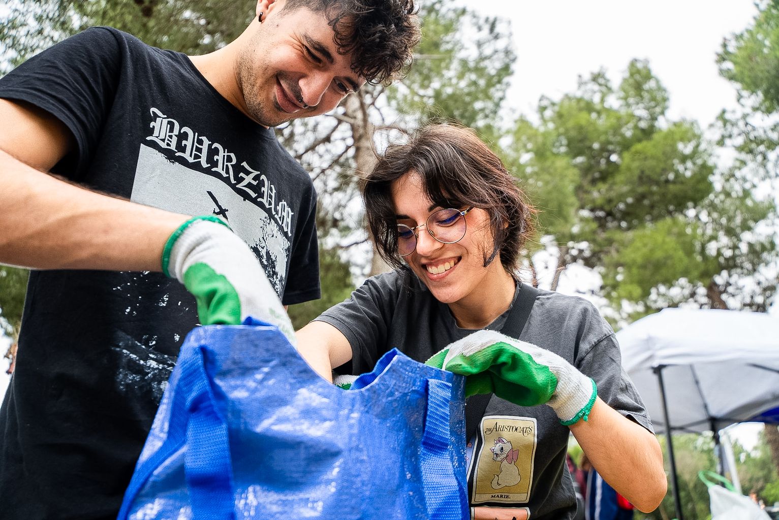 Uns joves buiden una de les bosses de recollida de residus recol·lectats a la neteja forestal a la muntanya Pelada.