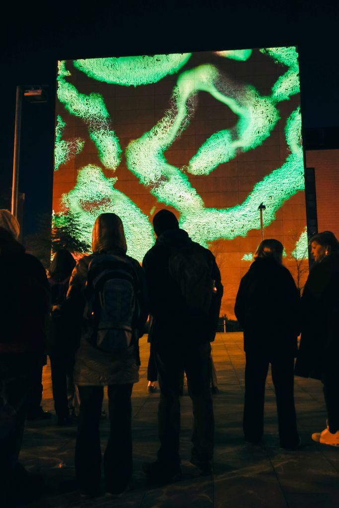 Siluetes davant la projecció de la instal·lació artística 'Terraform', d'Oxoo, al Festival Llum BCN 2025.