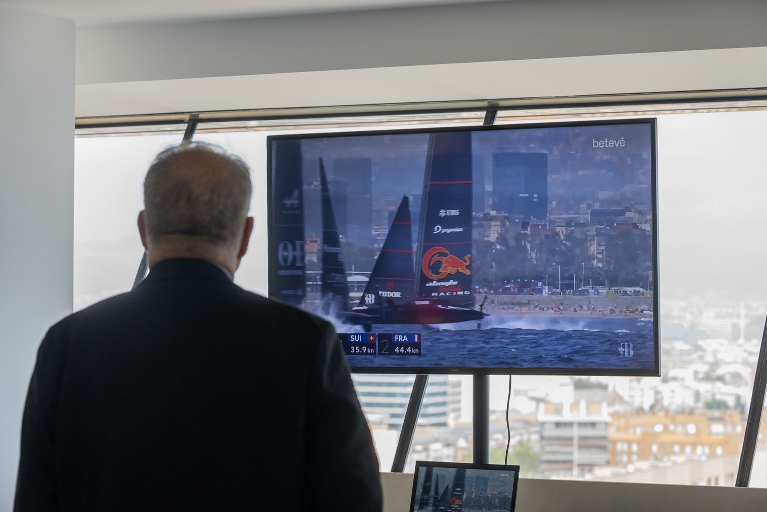 Assitent mirant una pantalla on es retransmet la primera regata de la Copa Amèrica des de l’AC37 CLUB