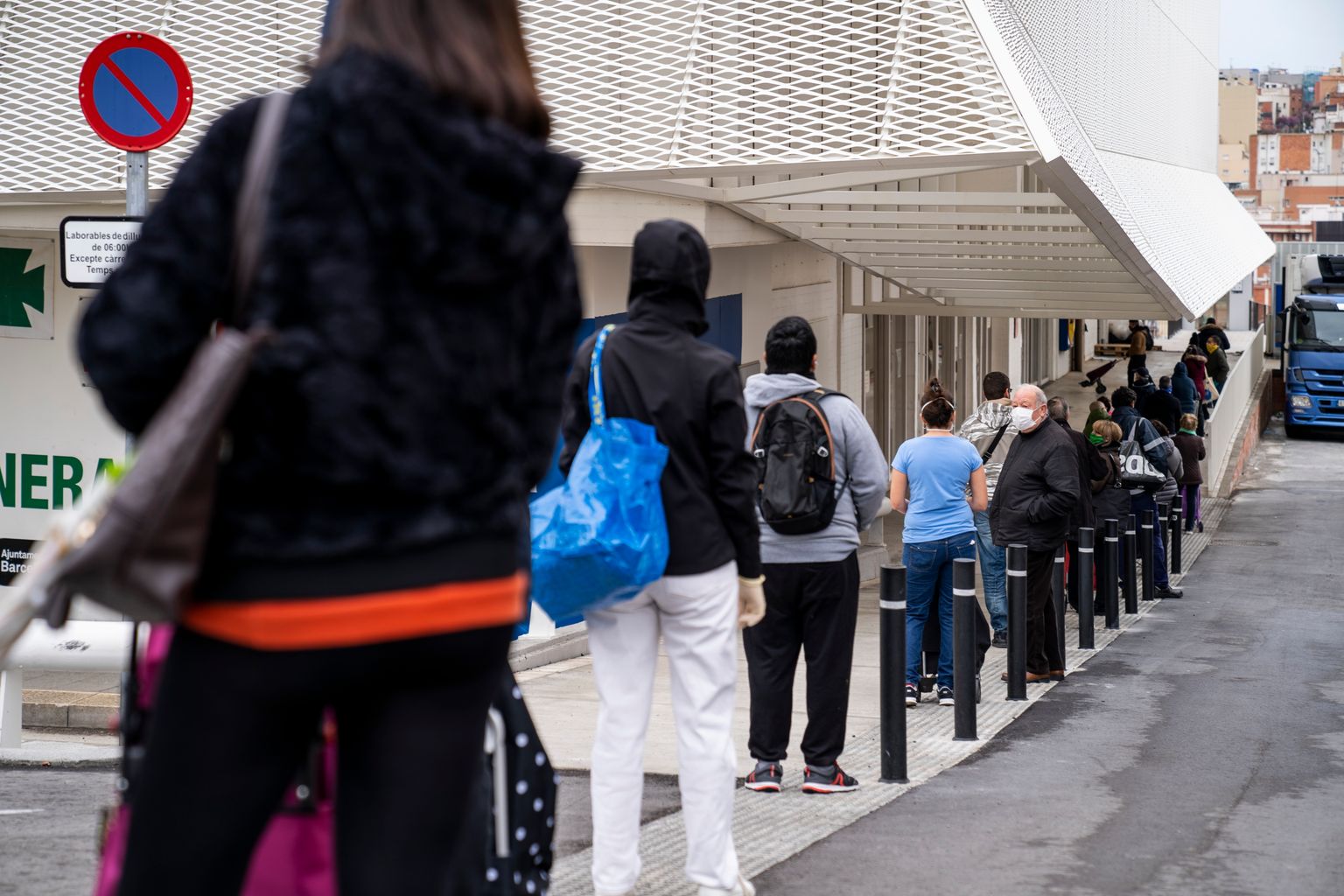 Cua de gent als voltants del Mercat de la Vall d’Hebron on hi ha també un hipermercat esperant per entrar. Molts d’ells porten mascaretes i guarden la distància de seguretat