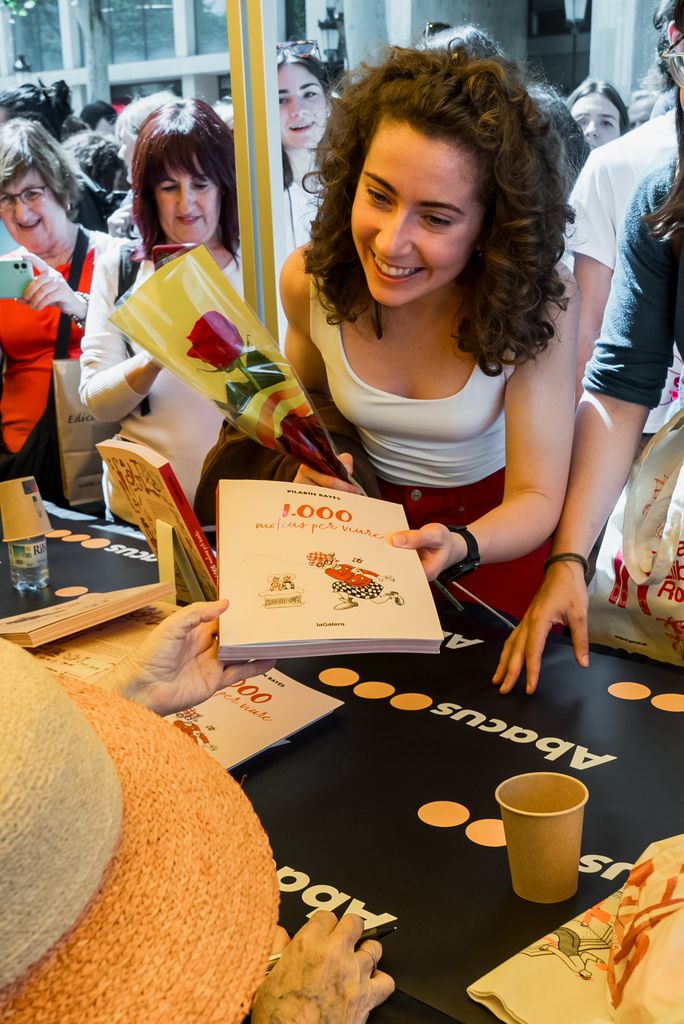 Una chica joven le da un libro para firmar a Pilarín Bayés el Día de Sant Jordi