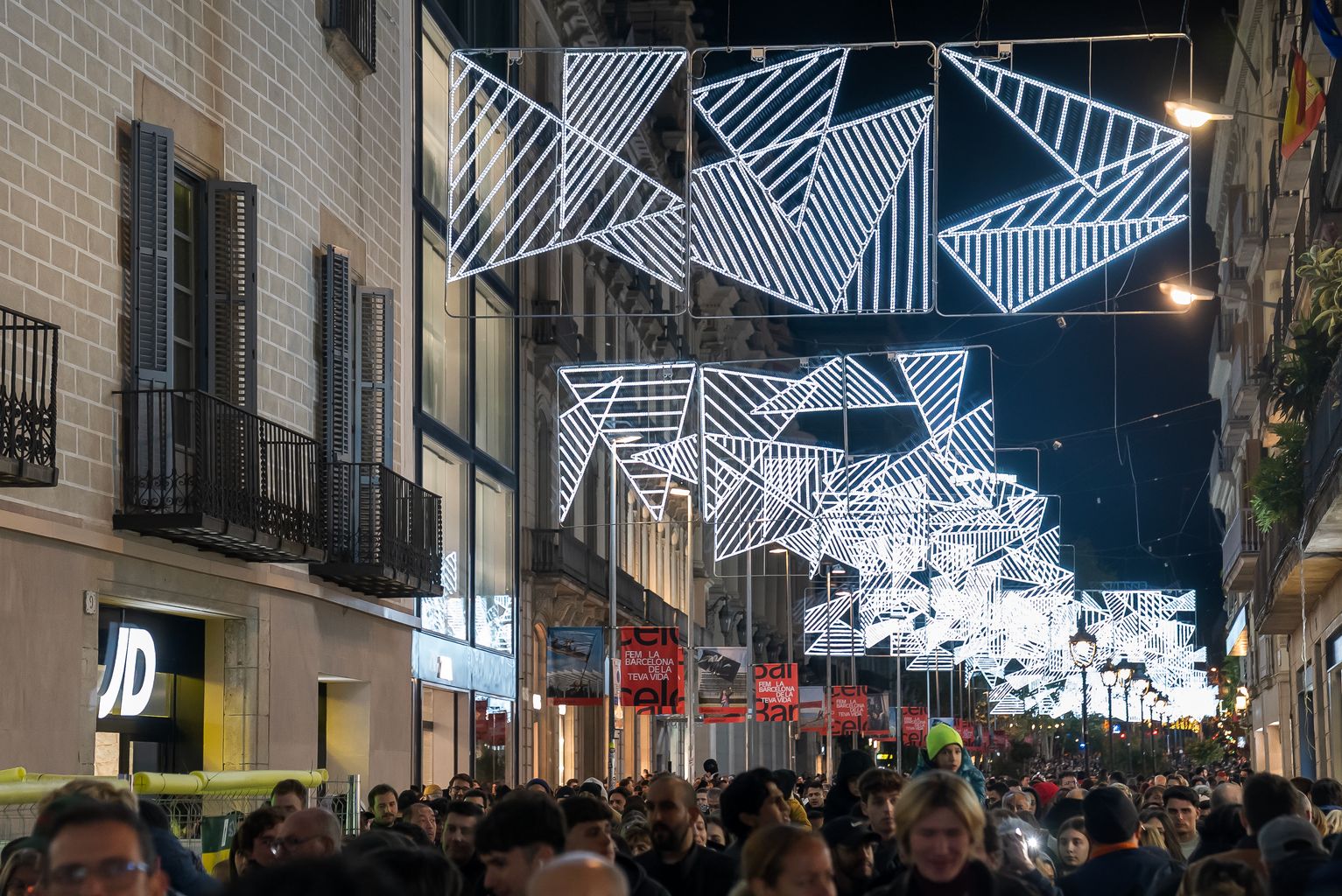 Gent passejant i mirant els llums de Nadal el dia de l’encesa de llums