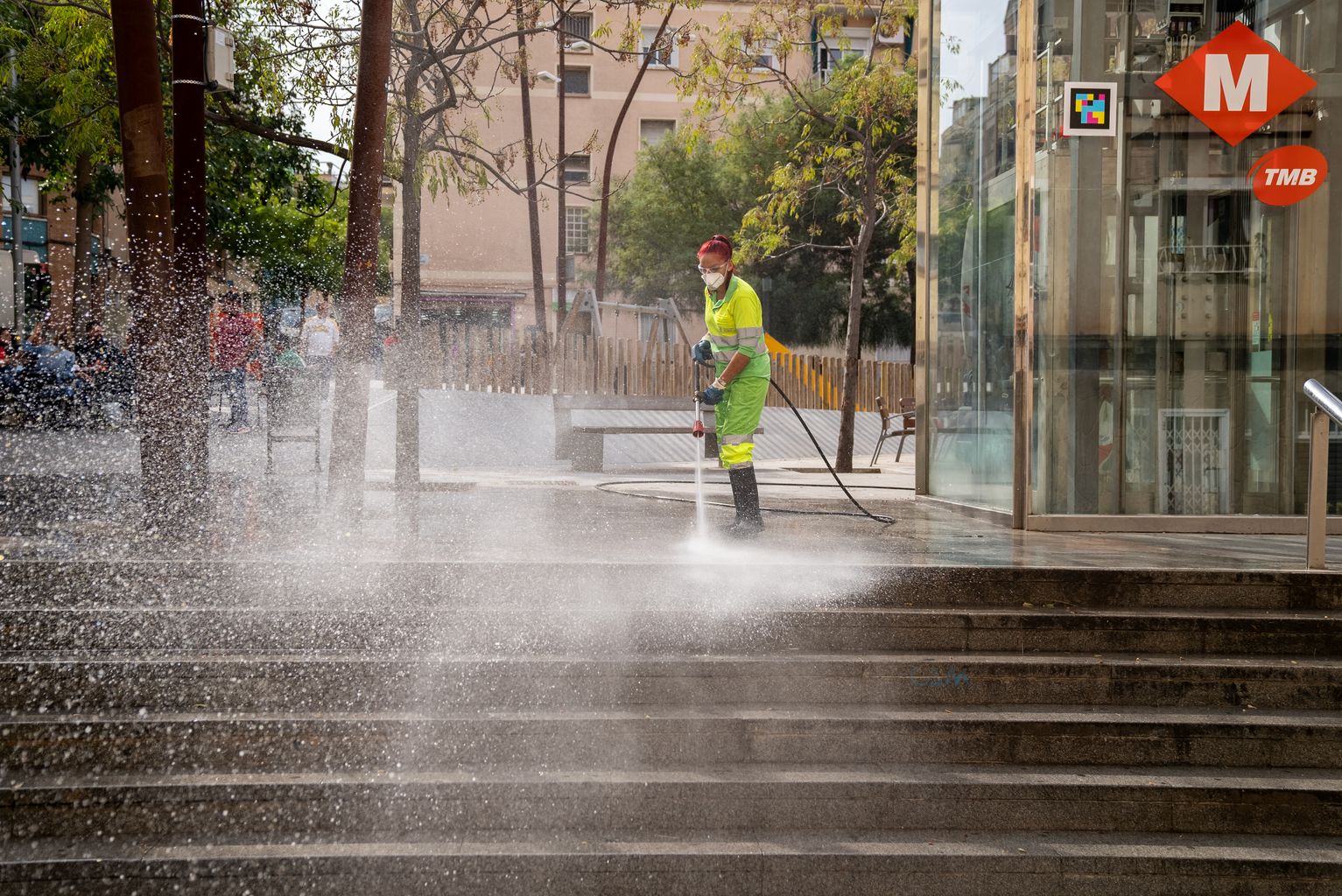 Una trabajadora del Servicio de Limpieza lava con agua a presión el pavimento de las escaleras de la plaza de Pastrana