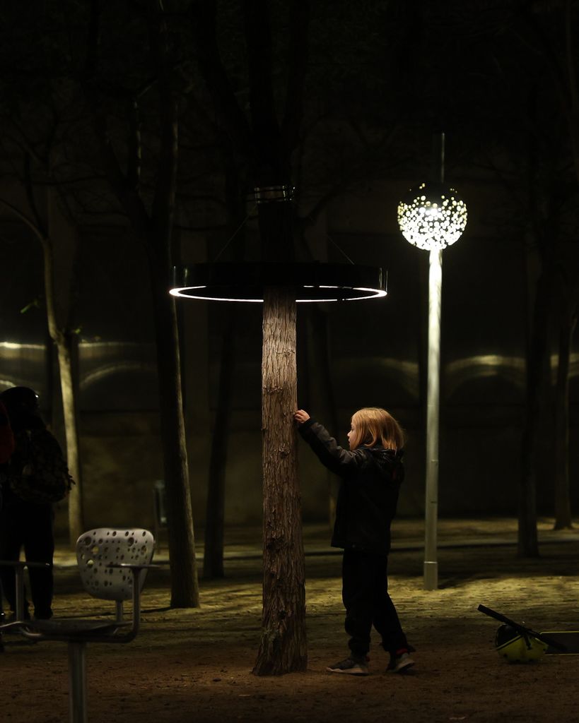 Una nena toca un arbre enllumenat. “LOOP”. Obra de la Universitat Internacional de Catalunya. Al Parc del Centre de Poblenou - MUHBA - c. Espronceda, 142-146