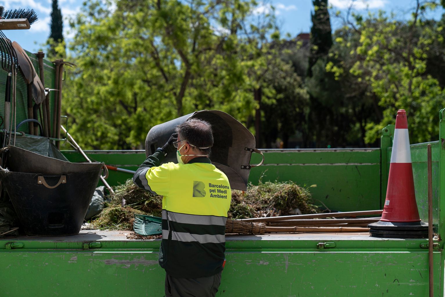 Un dels jardiners agafa les eines del camió de servei de Barcelona pel Medi Ambient
