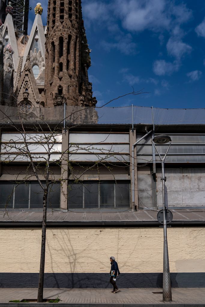 Un hombre camina por la calle y, detrás, la Sagrada Família. Distrito de L’Eixample. Barrio de la Sagrada Família.