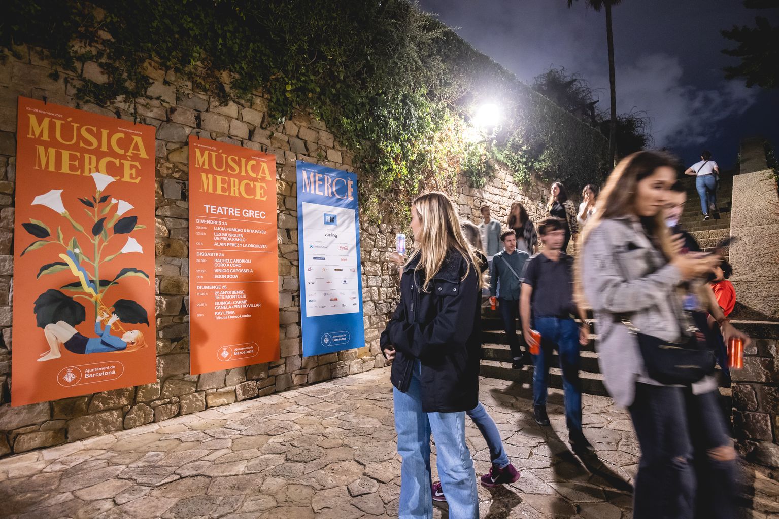 Gent sortint d’un concert del Teatre Grec amb els cartells de Música Mercè amb la programació