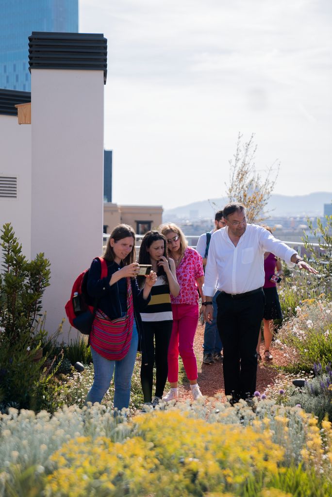 Grups de visitants a la coberta verda d'un edifici d'habitatges, a l'avinguda de la Diagonal, escoltant les explicacions d'un dels guies