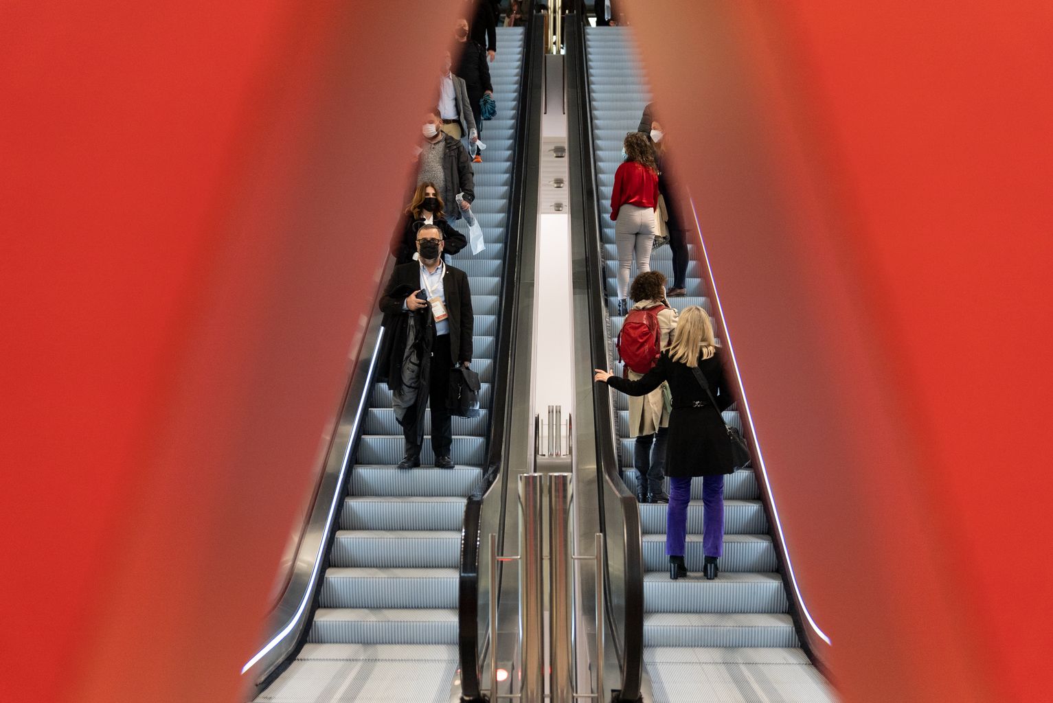 Gent pujant i baixant per les escales mecàniques del Disseny HUB on tenen lloc les  II Jornades de Reactivació Econòmica REACT