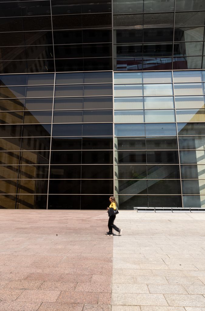 Façana del CCCB en el moment en què una dona creua pel mig de la plaça.