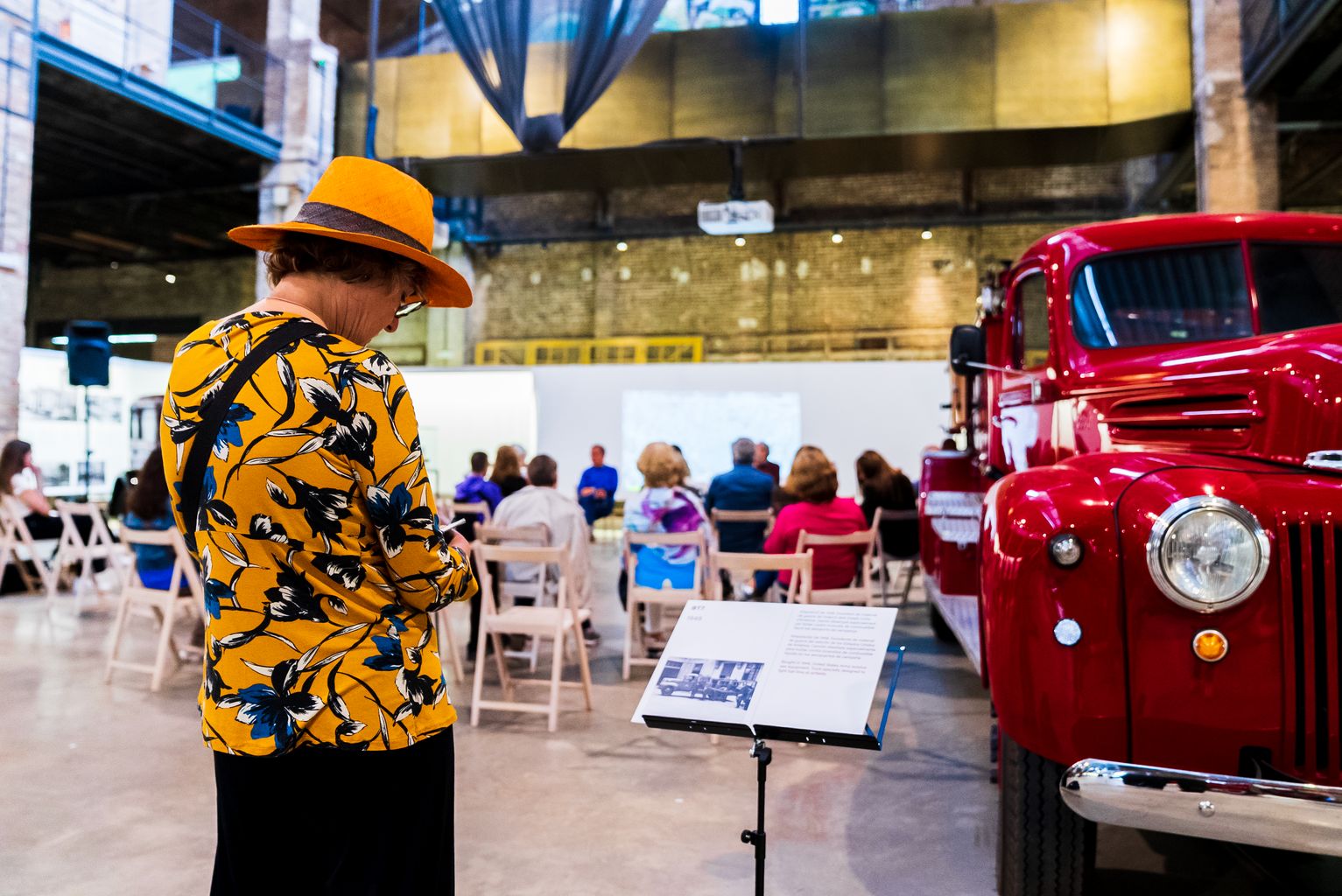 Una dona al centre d'història MUHBA Oliva Artés. De fons, el col·loqui de la Festa d'Arquitectura de Sant Martí del Model. Festival d'Arquitectures 2023