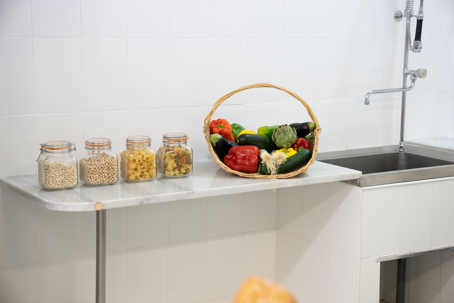 Cuina decorada amb un cistell de fruites i verdures i envasos de vidre amb pasta i llegums del Palauet Albéniz