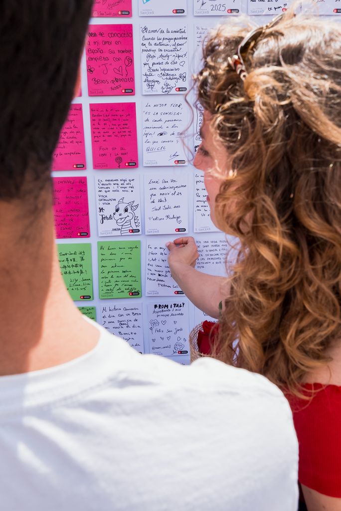 Una mujer mira el mural participativo ‘Una historia de Sant Jordi’, que consiste en una rosa hecha con historias sobre la leyenda de Sant Jordi