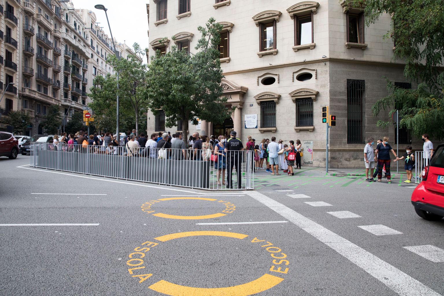 Senyalització horitzontal a la calçada de la travessera de Gràcia, que avisa de la proximitat d’una escola. Hi ha famílies amb nens al voltant de la zona pacificada de l’Escola Pia Balmes