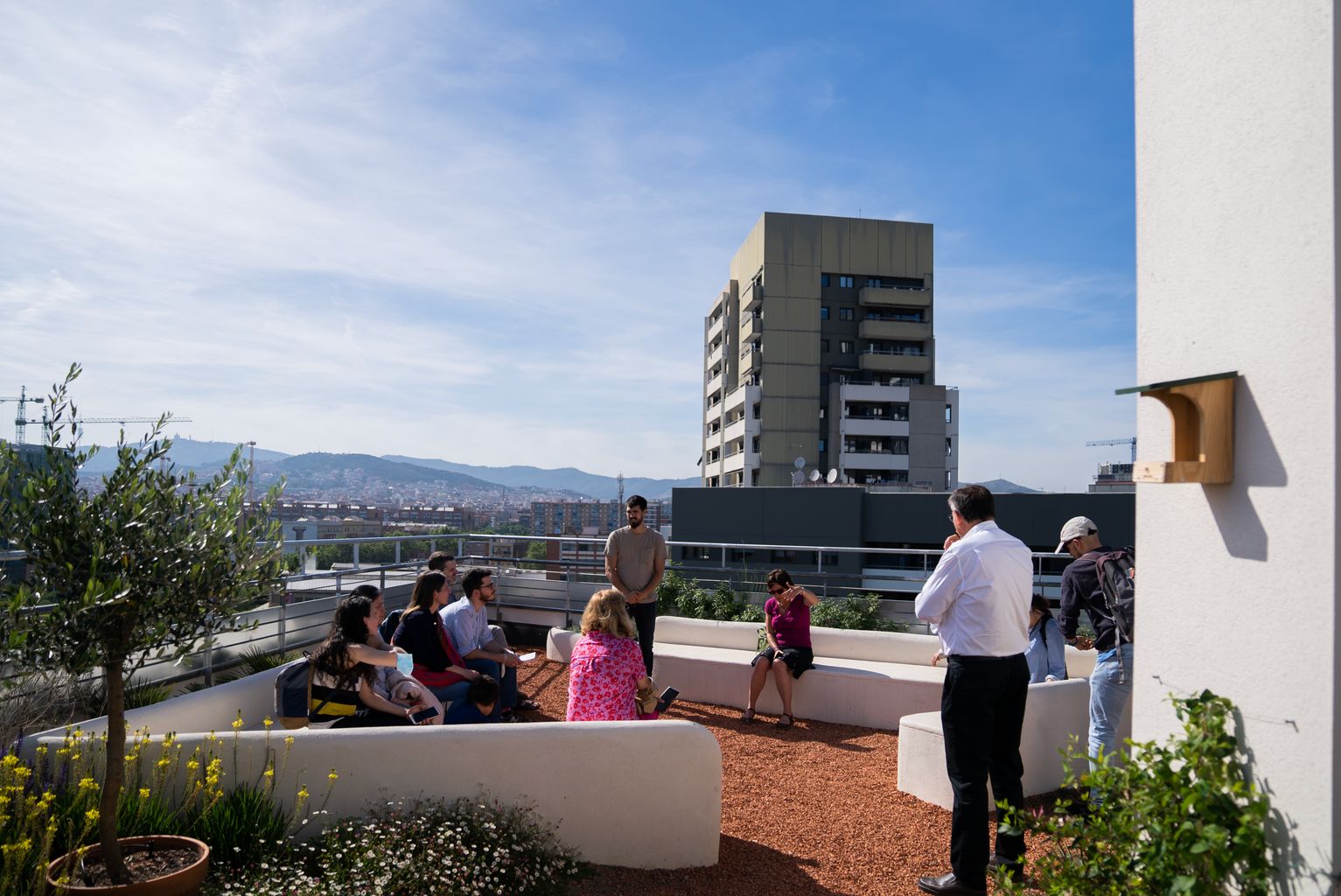 Grups de visitants asseguts al terrat de la coberta verda d'un edifici d'habitatges, a l'avinguda de la Diagonal